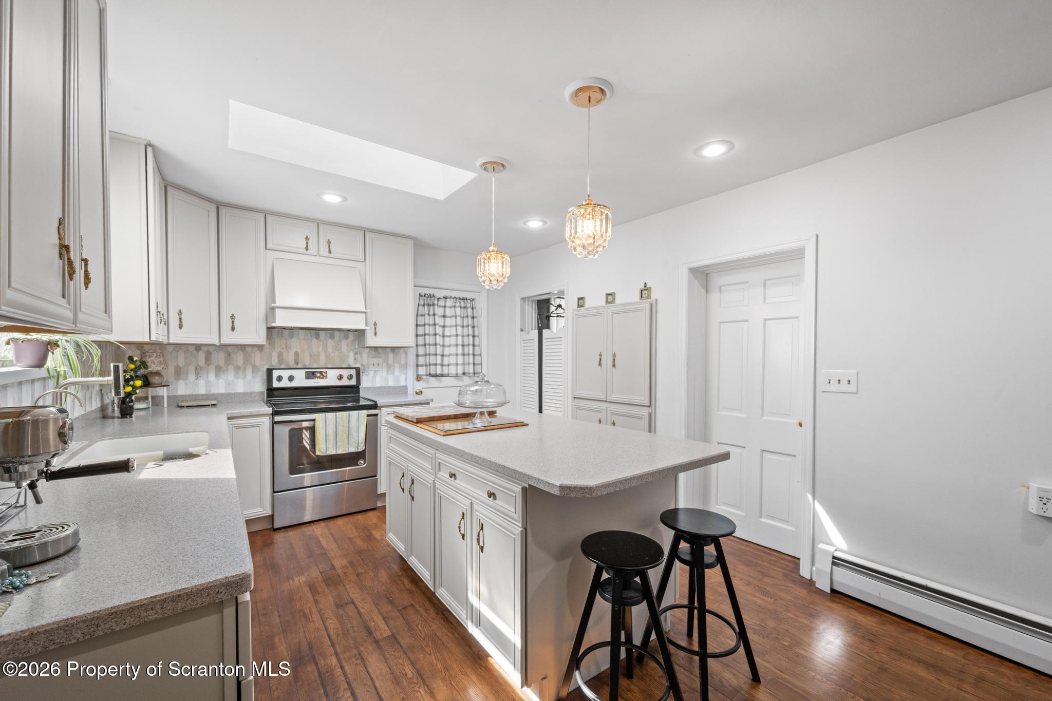 502 Gravel Pond Road Clarks Summit, PA 18411 - Photo 17 of 91 a kitchen with a sink a stove a refrigerator and white cabinets with wooden floor