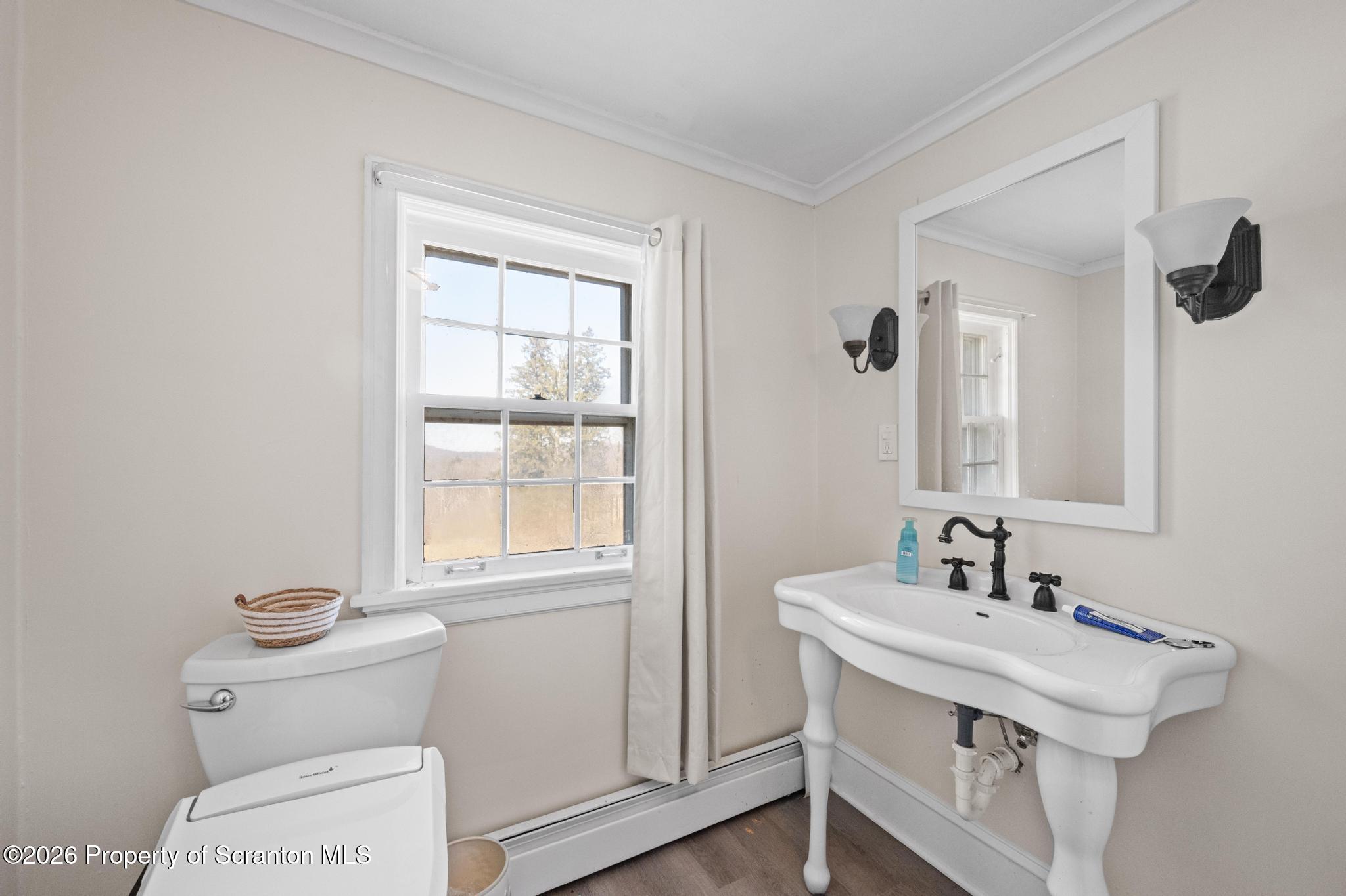 502 Gravel Pond Road Clarks Summit, PA 18411 - Photo 57 of 91 a bathroom with a toilet a sink a mirror and a window