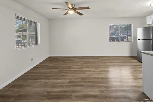 a view of an empty room with window and wooden floor