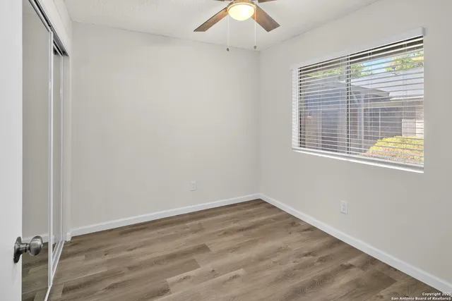 an empty room with windows and fan