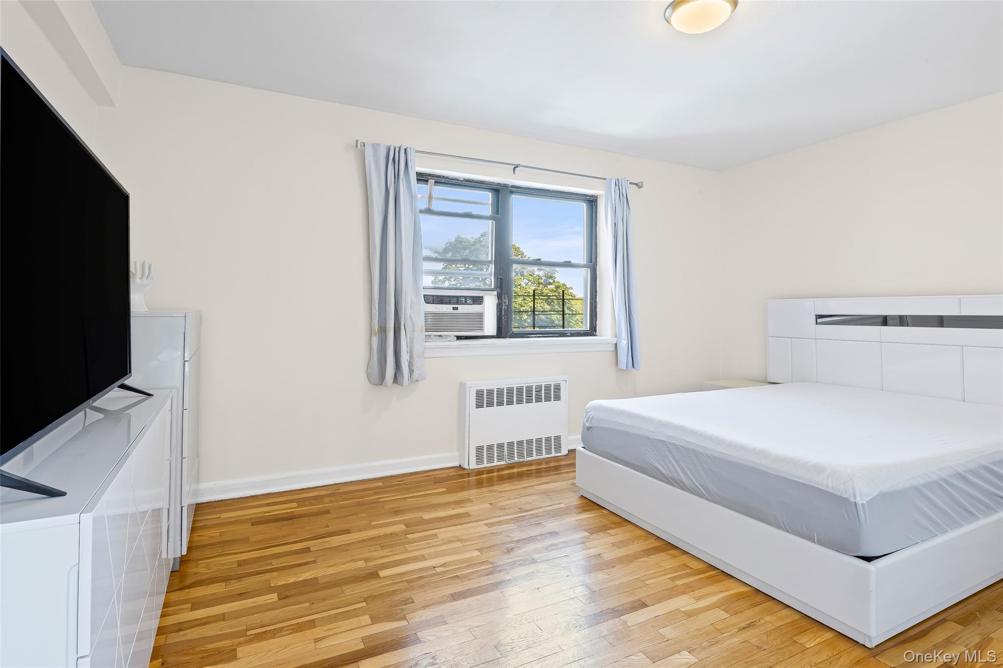147-10 84th Road, Unit 4G Queens, NY 11435 - Photo 7 of 13 Bedroom featuring light wood finished floors and radiator