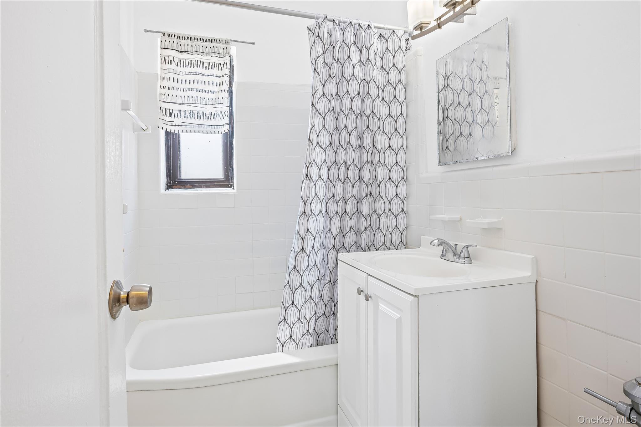 147-10 84th Road, Unit 4G Queens, NY 11435 - Photo 9 of 13 Bathroom featuring vanity, shower / tub combo, and tile walls