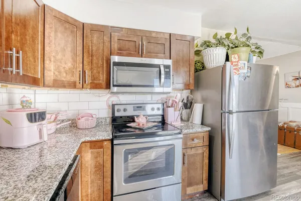 a kitchen with stainless steel appliances granite countertop a refrigerator a stove a dining table and chairs