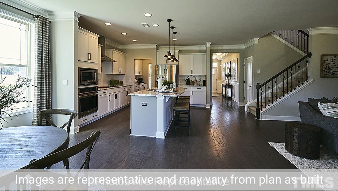 7704 Calcutta Drive Willow Spring, NC 27592 - Photo 8 of 30 a open kitchen with stainless steel appliances kitchen island granite countertop a stove top oven a sink a dining table and chairs