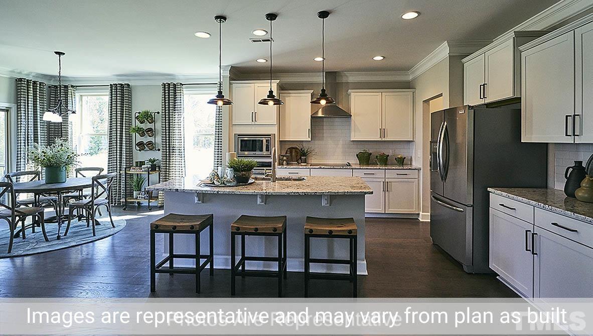 7704 Calcutta Drive Willow Spring, NC 27592 - Photo 9 of 30 a kitchen with stainless steel appliances kitchen island granite countertop a table chairs sink and cabinets