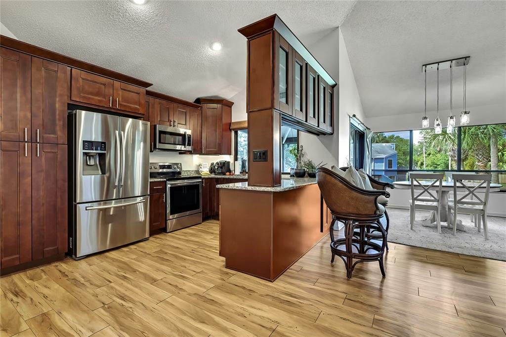 2919 North Rivers Edge Boulevard, Unit 2919 Crystal River, FL 34429 - Photo 11 of 36 a kitchen with stainless steel appliances granite countertop a refrigerator a stove a sink a dining table and chairs with wooden floor
