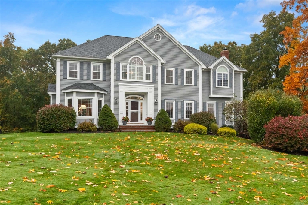 a front view of a house with garden and trees