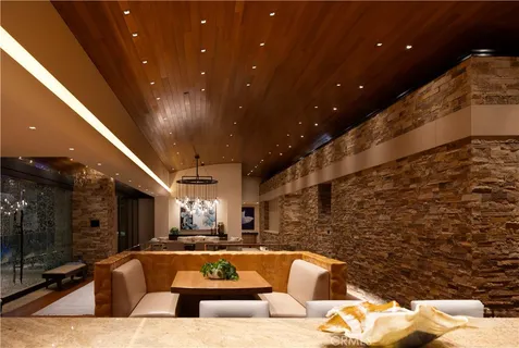 a living room with couches floor to ceiling window and a flat screen tv