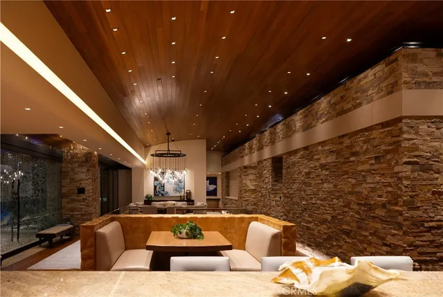 a living room with couches floor to ceiling window and a flat screen tv