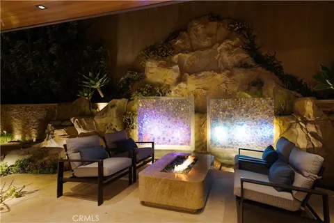 a view of a patio with couches table and chairs under an umbrella with large trees