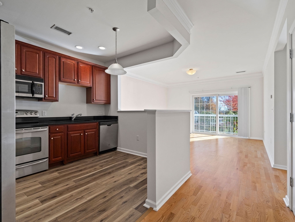 170 Clocktower Drive, Unit 5103 Waltham, MA 02452 - Photo 5 of 29 a kitchen with stainless steel appliances granite countertop a stove a sink and a refrigerator with wooden floors