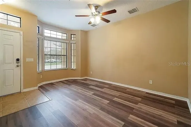 a view of an empty room with window and wooden floor