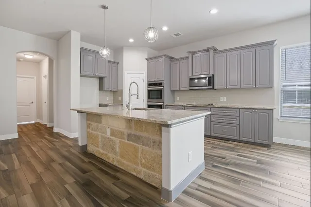a kitchen with stainless steel appliances granite countertop a stove a sink and a refrigerator