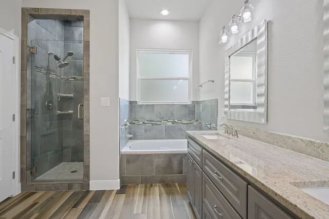 a bathroom with a granite countertop sink a large mirror a bathtub and shower