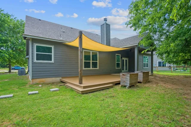 a view of a house with a backyard and a large tree