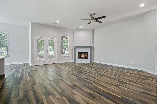 an empty room with wooden floor a ceiling fan and windows
