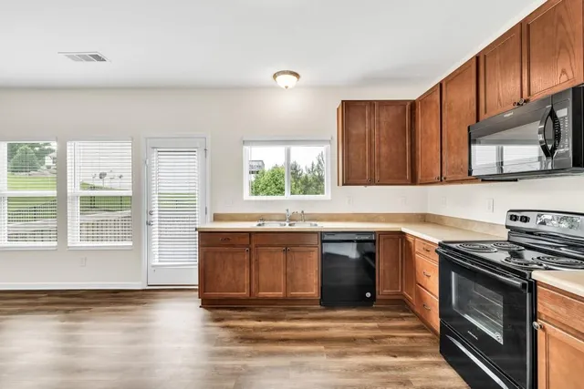 a view of a kitchen with wooden floor and windows