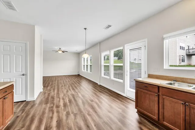 a view of a room with wooden floor staircase and a kitchen space