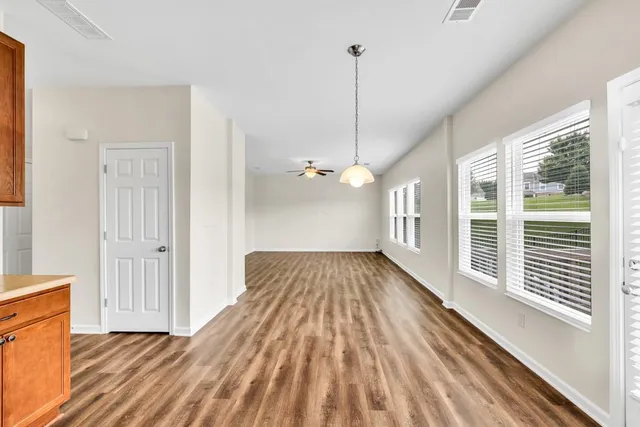a view of an empty room with a window and wooden floor