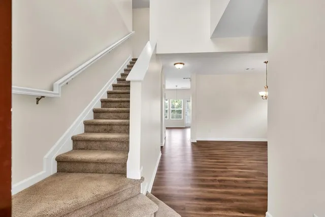 a view of a hallway with wooden floor and a bathroom