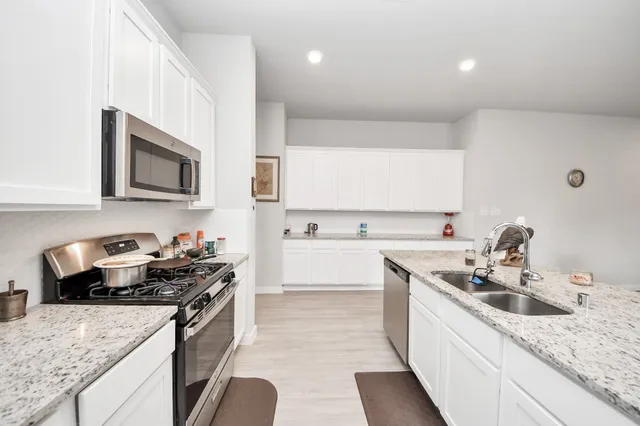 a kitchen with granite countertop stainless steel appliances a sink a stove top oven a counter space and cabinets