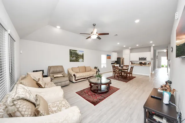 a living room with furniture kitchen view and a chandelier
