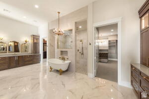 1141 East Lost Ridge Drive Washington, UT 84780 - Photo 65 of 108 Spacious bathroom featuring a freestanding clawfoot tub, dual shower heads within a glass-enclosed shower, extensive vanity with three framed mirrors, and a chandelier light fixture