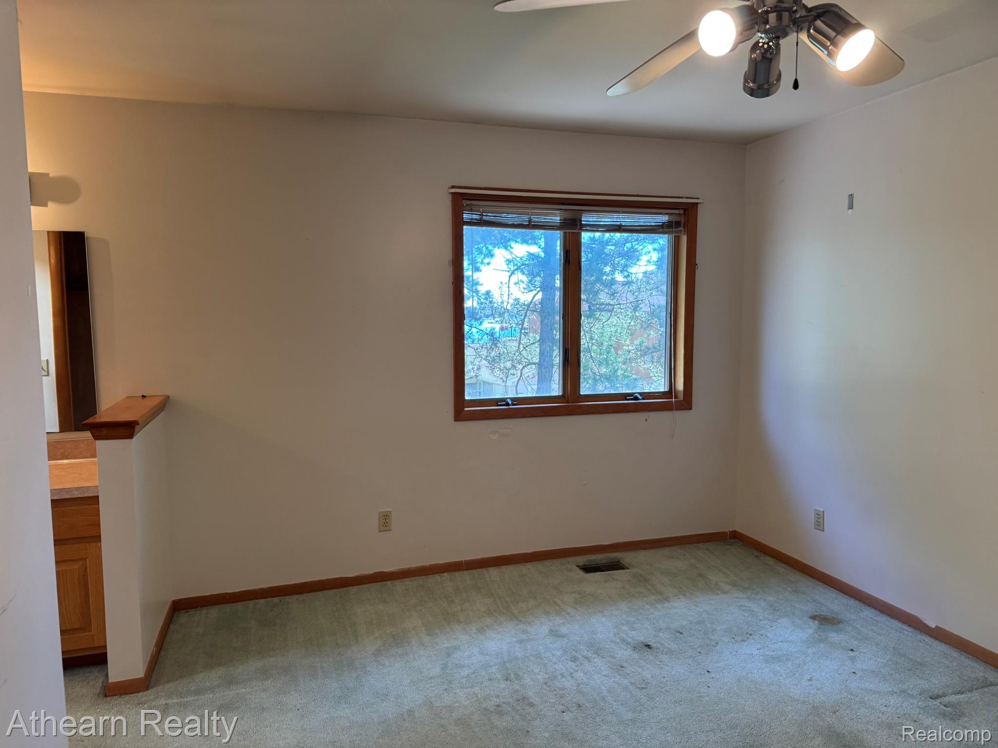 11449 Torrey Road Fenton, MI 48430 - Photo 27 of 30 Natural light from a wooden framed window, accompanied by a ceiling fan with integrated lighting, and a partial vanity with a wood-finish cabinet
