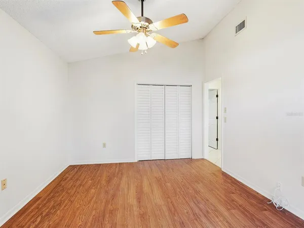 a view of a big room with wooden floor and a chandelier fan