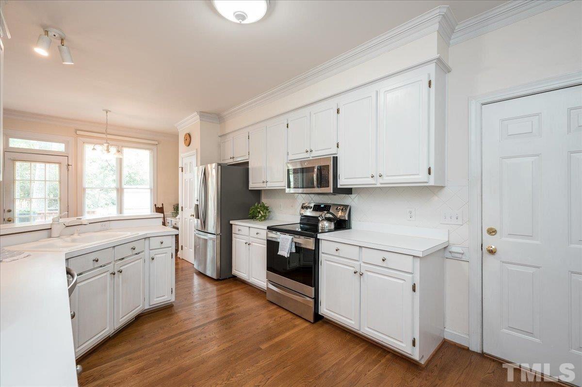 8813 Cottingham Way Raleigh, NC 27615 - Photo 5 of 27 a kitchen with granite countertop white cabinets and white appliances