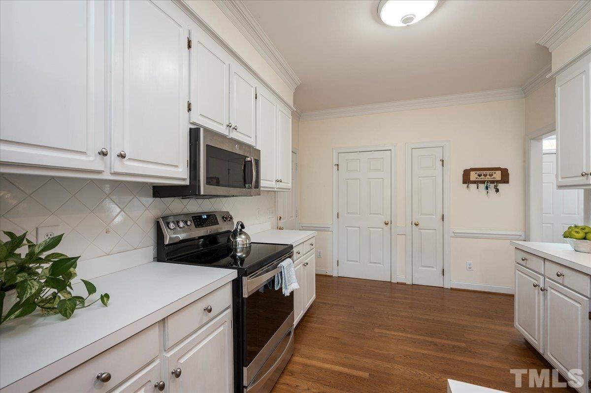 8813 Cottingham Way Raleigh, NC 27615 - Photo 7 of 27 a kitchen with stainless steel appliances a stove a microwave and cabinets