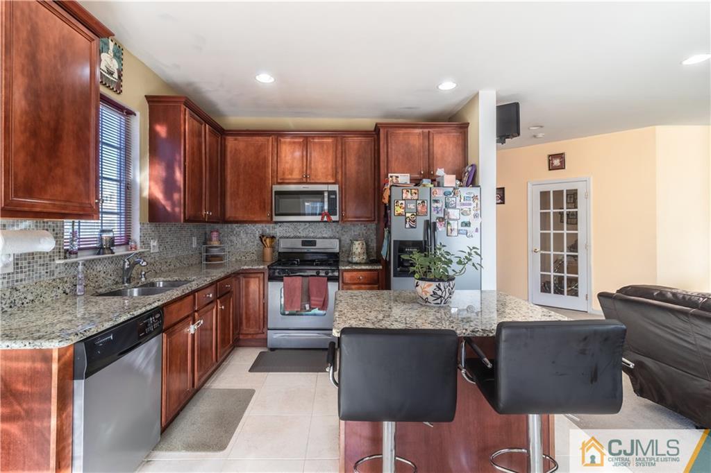 4 Seneca Lane Bordentown, NJ 08505 - Photo 8 of 29 a kitchen with stainless steel appliances granite countertop a stove a sink dishwasher a microwave oven and a dining table with wooden cabinet