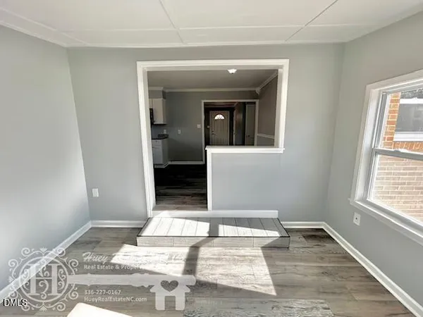 a view of a hallway to a bedroom with wooden floor and a window