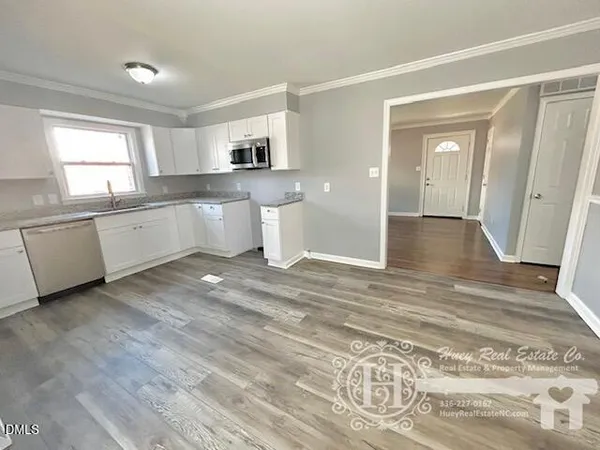 a large white kitchen with window and stainless steel appliances
