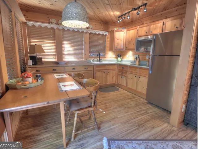 a kitchen with a table chairs refrigerator and wooden cabinets