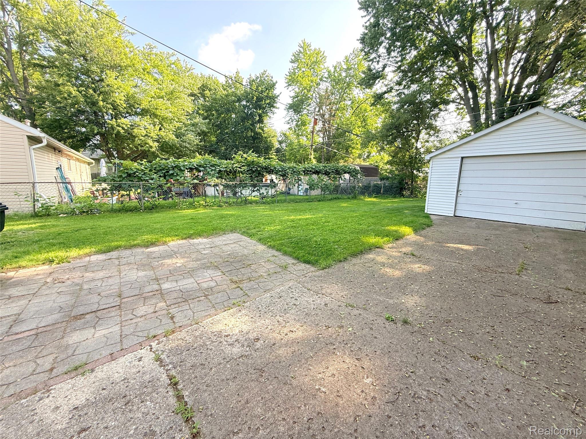 21212 Rensselaer Street Farmington, MI 48336 - Photo 11 of 11 Spacious backyard featuring a detached garage with white siding, a concrete driveway, a paver patio area, and a manicured lawn