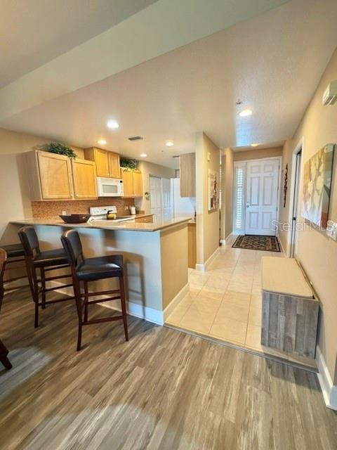 13413 Gasparilla Road, Unit 304 Placida, FL 33946 - Photo 8 of 28 a open kitchen with kitchen island a stove a refrigerator a sink dishwasher with a dining table and chairs with wooden floor