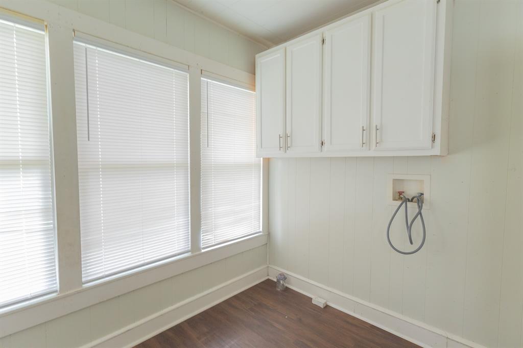 2913 Homan Avenue, Unit 2913 Waco, TX 76707 - Photo 16 of 16 Laundry area featuring three large windows with blinds, wood-finish flooring, white wall paneling, and upper cabinetry