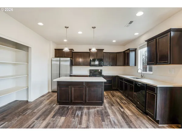 a kitchen with stainless steel appliances granite countertop a stove top oven a sink dishwasher a microwave oven and a refrigerator with wooden floor