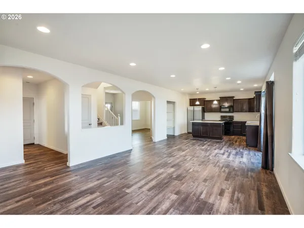 a view of an empty room with wooden floor and a fireplace