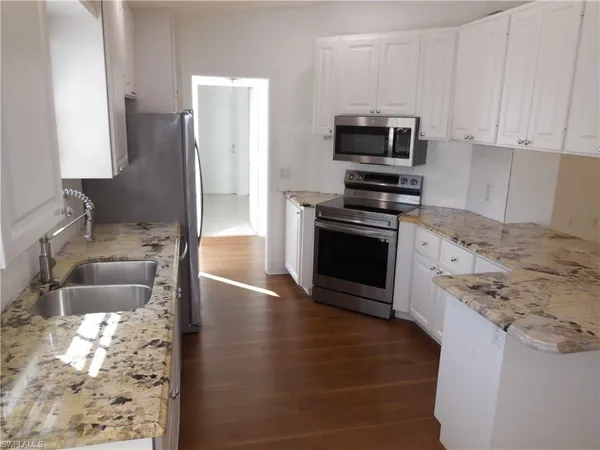 a kitchen with granite countertop a stove and a wooden floor