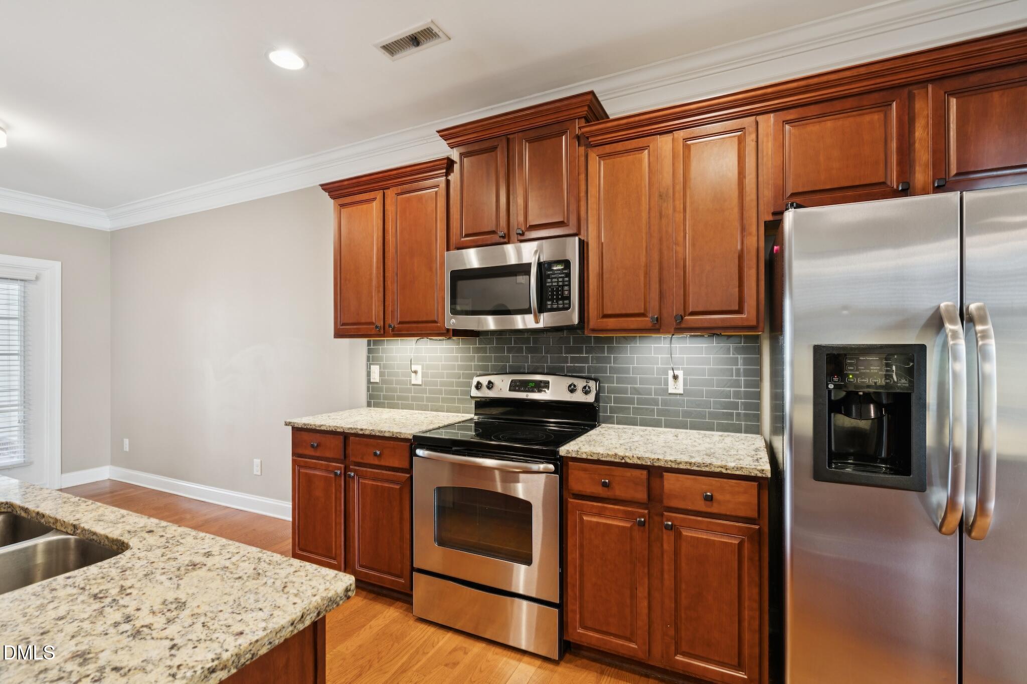616 Democracy Street Raleigh, NC 27603 - Photo 27 of 61 a kitchen with stainless steel appliances granite countertop wooden cabinets a stove top oven a sink and dishwasher