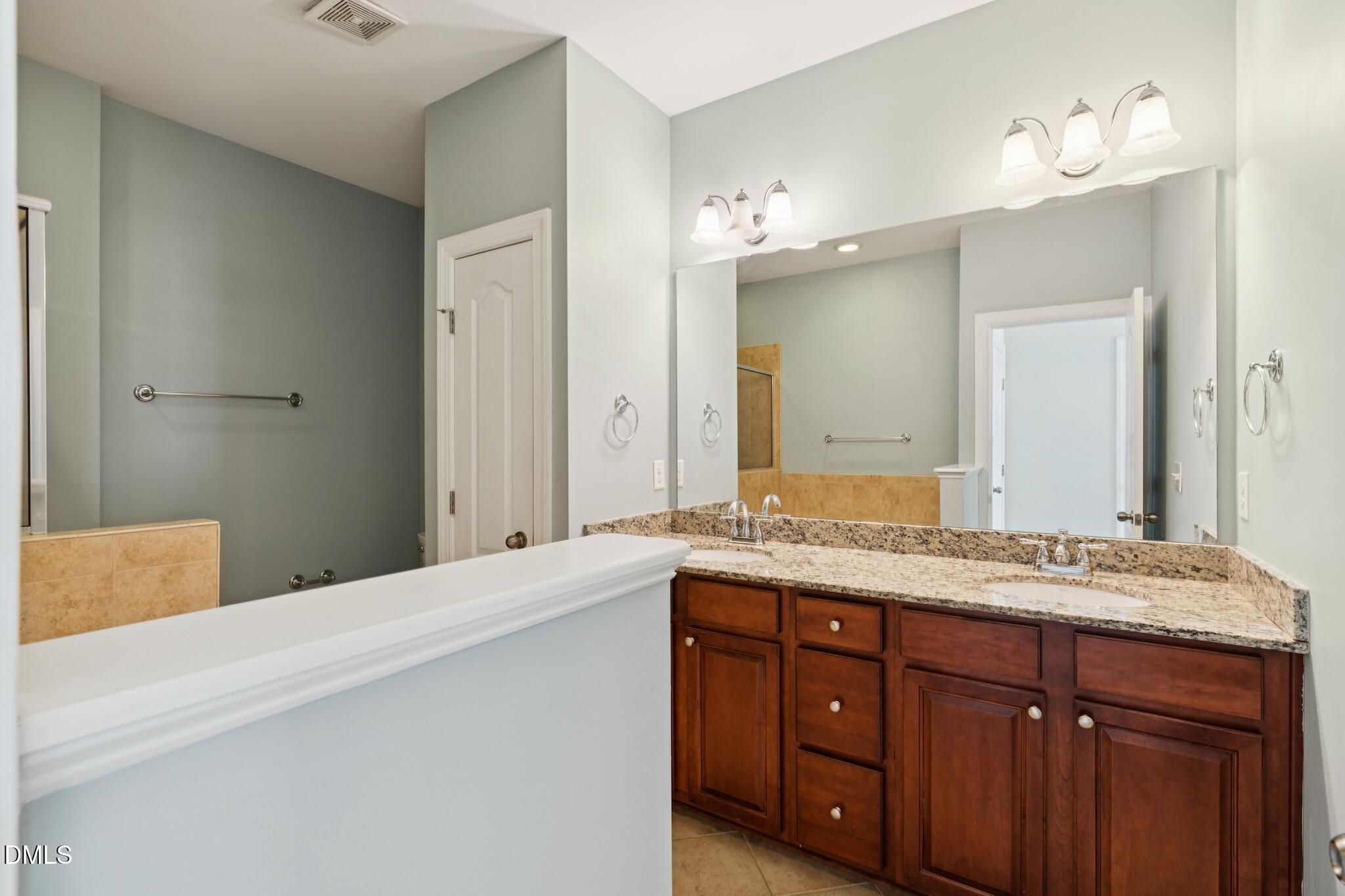 616 Democracy Street Raleigh, NC 27603 - Photo 46 of 61 a bathroom with a granite countertop double vanity sink and mirror