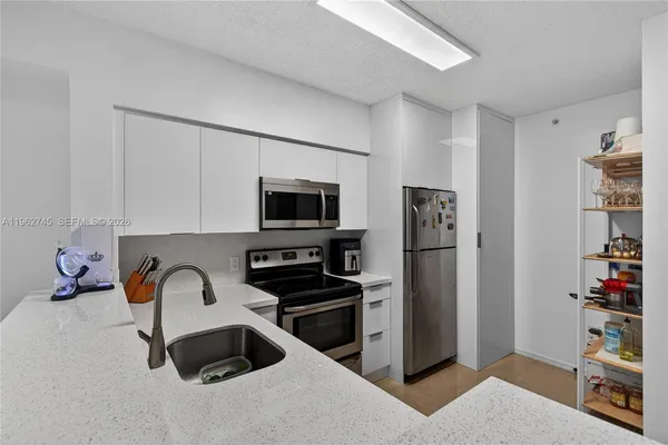 a kitchen with stainless steel appliances a refrigerator a stove a microwave and a dining table