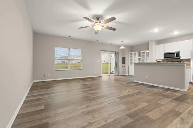 a view of an empty room with window and wooden floor