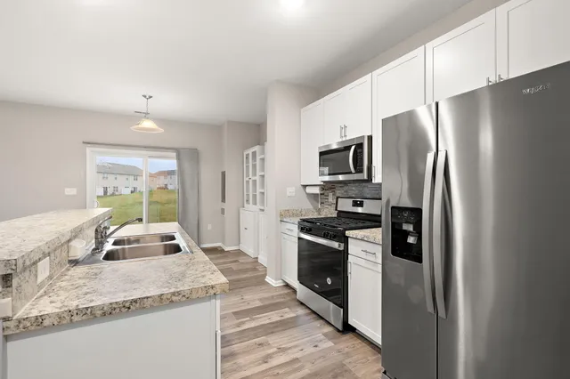 a kitchen with granite countertop kitchen island stainless steel appliances a refrigerator stove and sink