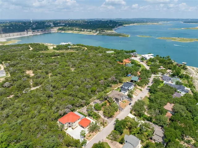 an aerial view of a residential houses with outdoor space and lake view