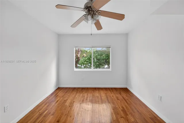 an empty room with a window and a ceiling fan