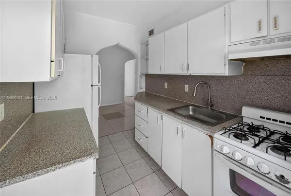 a kitchen with granite countertop a sink a stove and cabinets