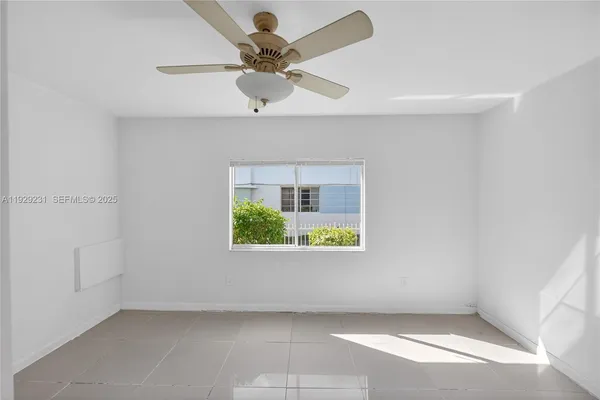 an empty room with a window and a ceiling fan